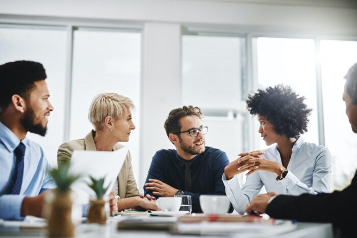 A group of managers engage in lively conversation in a conference room.