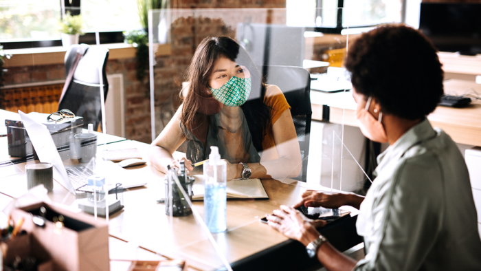 Two women talking in an office wearing face masks