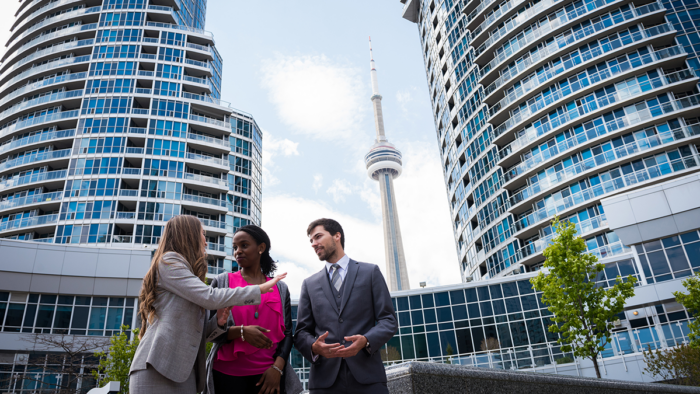 three colleagues, one white woman, one black woman and one white man, meeting outside of an office building