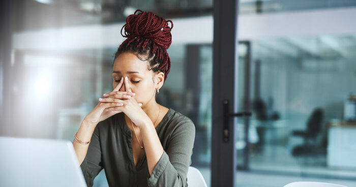 Shot of a young businesswoman looking stressed out while working in an office