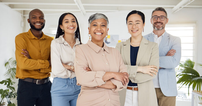 diverse group of professional employees looking at the camera and smiling.